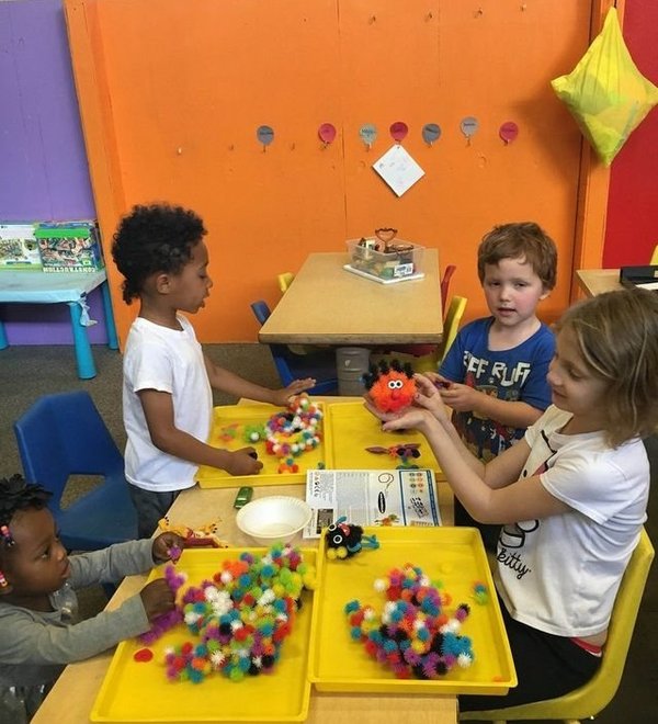 Young children playing with colorful materials at a classroom table at Super Kidz Club