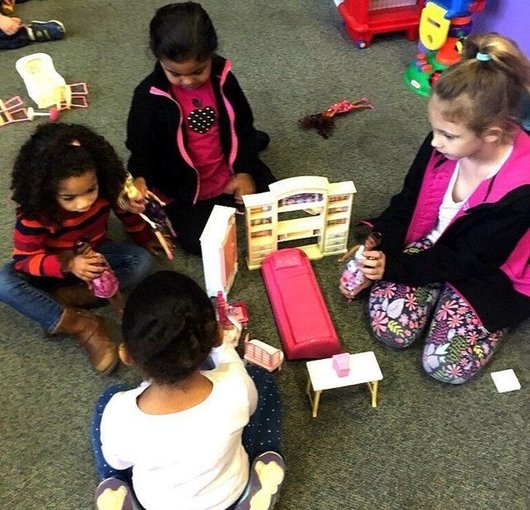 Preschoolers playing with a dollhouse together